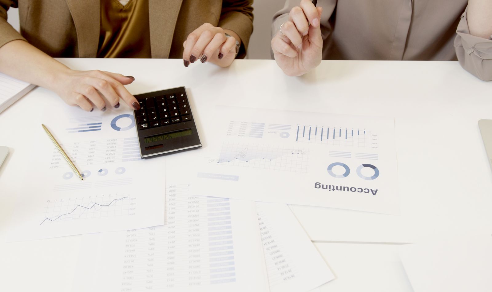 Profesionales analizando estados financieros con calculadora y gráficas